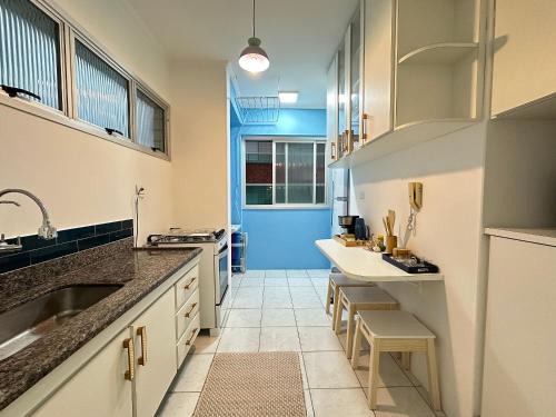 une cuisine avec des placards blancs et une porte bleue dans l'établissement Vista deslumbrante e elegância frente mar!, à Vila Balneária