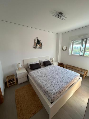 a white bedroom with a large bed and two windows at Oliva Sol Apartment in Oliva