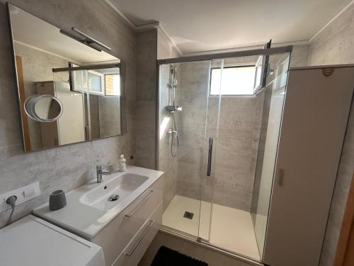 a bathroom with a shower and a sink and a mirror at Oliva Sol Apartment in Oliva