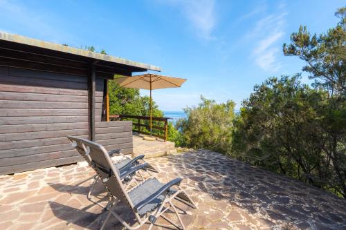 a pair of chairs and an umbrella on a patio at Casette nel Parco in Portoferraio