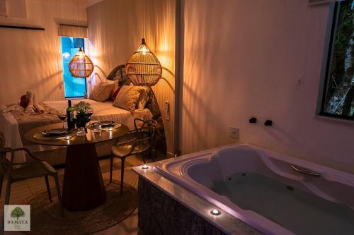 ein Badezimmer mit Badewanne, Tisch und Couch in der Unterkunft DA MATA Chalés in Lindóia
