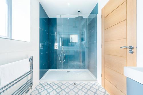 a bathroom with a shower with blue tiles at 4 Bed in Woolfardisworthy oc-s32421 in Woolfardisworthy