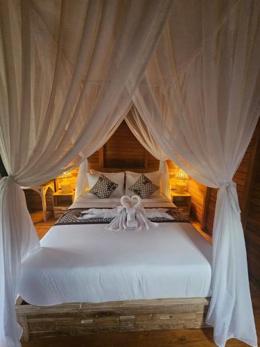 a bedroom with a white bed with curtains at Arta Dani villas in Sidemen