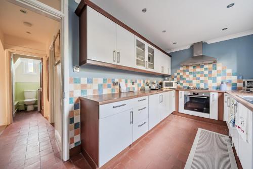 eine Küche mit weißen Schränken und blauen Wänden in der Unterkunft Spacious Berkshire home - Perfect for groups and contractors in Canvey