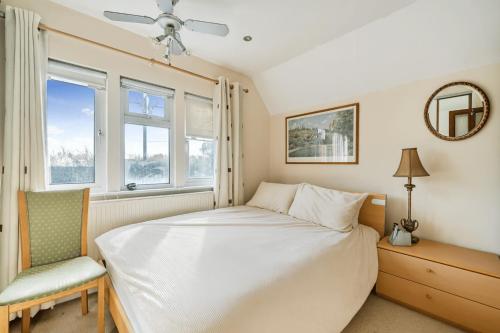 ein Schlafzimmer mit einem Bett und einem Stuhl und Fenstern in der Unterkunft Spacious Berkshire home - Perfect for groups and contractors in Canvey
