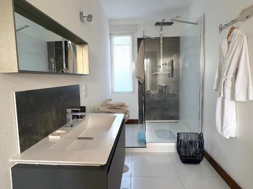 a white bathroom with a shower and a sink at Villa du Port in Sibiril
