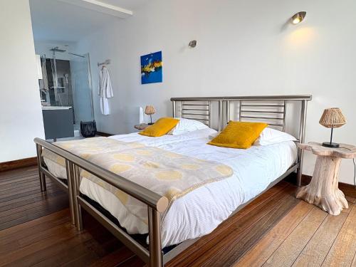 a bedroom with a large bed with two yellow pillows at Villa du Port in Sibiril