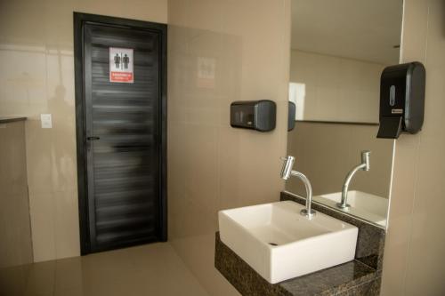 ein Badezimmer mit einem weißen Waschbecken und einer schwarzen Tür in der Unterkunft Apto Vista Mar Jogos Piscina 2 Suítes in São Bento