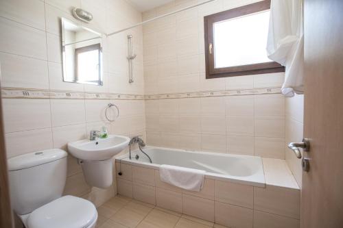 a bathroom with a toilet and a sink and a bath tub at Napiana Apartments in Ayia Napa