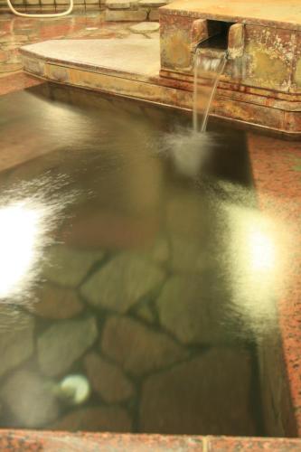 une piscine d'eau avec une fontaine dans l'établissement Kashiwaya, à Chikuma