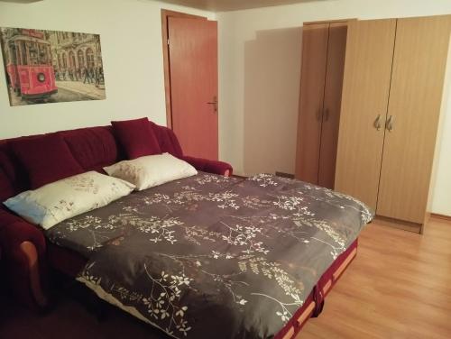 1 cama en la sala de estar con sofá rojo en Blossom Cottage - Sustainable Tourism Retreat, en Laktaši