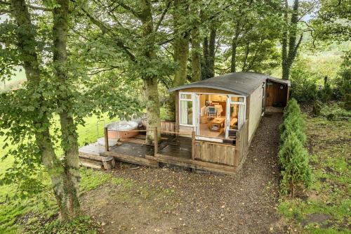 a cabin in the middle of a forest at The Hide - Cosy Cabin with hot tub in Newton