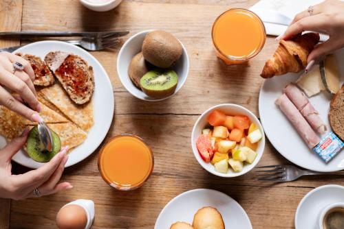 a wooden table topped with plates of breakfast foods at Hôtel Le Relais de Poste Arles Centre Historique in Arles
