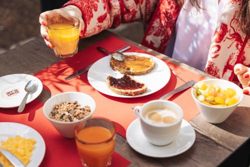 a table topped with plates of food and drinks at Hôtel Le Relais de Poste Arles Centre Historique in Arles