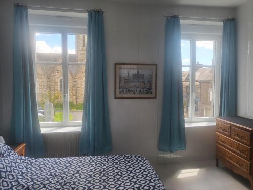 a bedroom with blue curtains and a bed and a window at Cozy Apartment in Fougerolles du Plessis in Fougerolles-du-Plessis