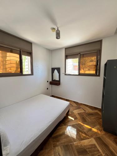 a bedroom with a white bed and two windows at Auberge guest house1 in Imsouane
