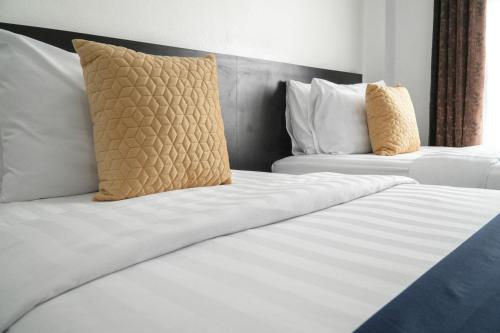 two beds in a hotel room with white sheets and pillows at Preme village in Ubon Ratchathani