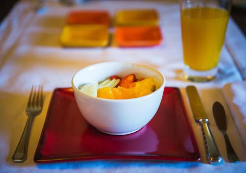 Un bol de fruta en una bandeja roja con un tenedor y jugo. en Rio Hermoso Hotel De Montaña, en San Martín de los Andes