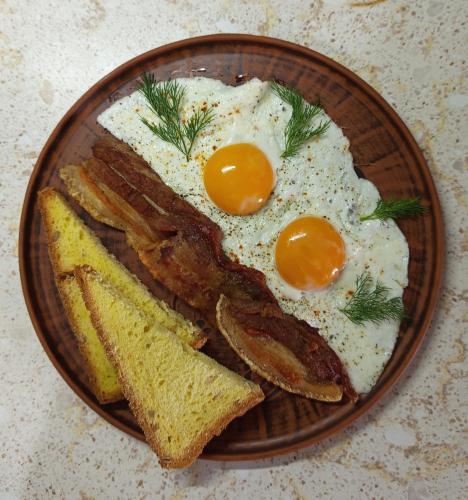une assiette avec deux œufs, du bacon et des toasts dans l'établissement El Rancho De Stayki, à Stayki