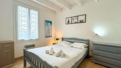 a bedroom with a bed with white sheets and a window at Charmante location au pied des dunes in Sainte-Marie-de-Ré