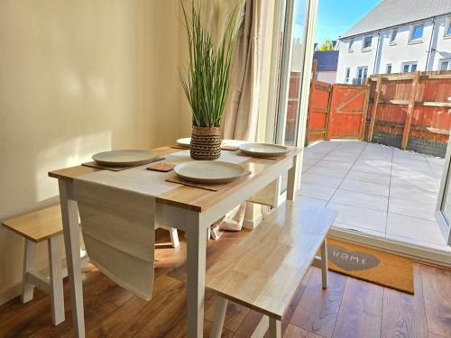 a table with plates and a potted plant on it at Family-Friendly 4-Bed Swansea Stay with Parking in Landore