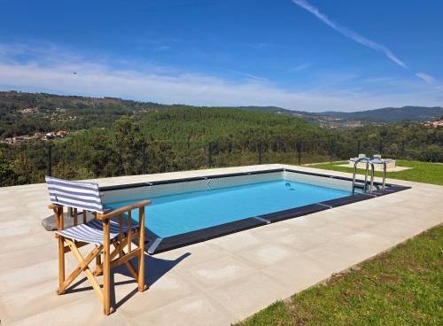 a swimming pool with a chair sitting next to it at Casa do Barbeiro - View of the River Minho in Melgaço