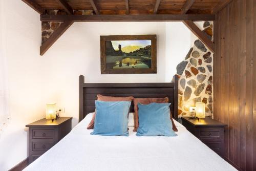 Un dormitorio con una cama con almohadas azules y una pintura en Home2Book Icod Rural Escape Pool BBQ, en El Amparo