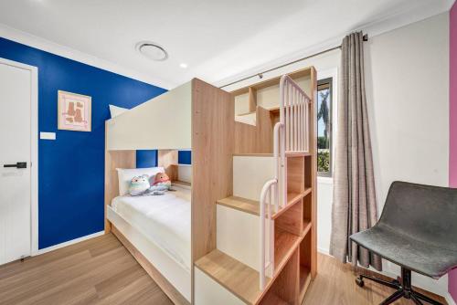 a small bedroom with a bunk bed and a chair at Sienna Arches - Modern Family Haven near Ocean Baths in The Entrance