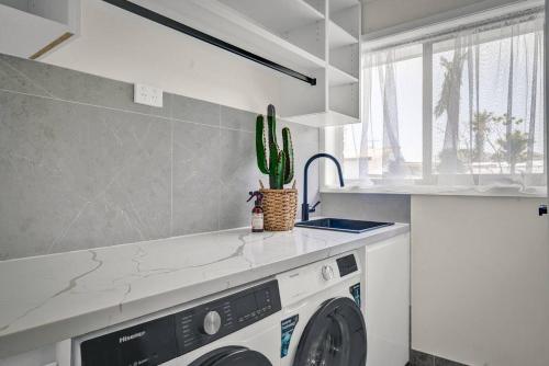 a kitchen with a washing machine and a sink at Sienna Arches - Modern Family Haven near Ocean Baths in The Entrance