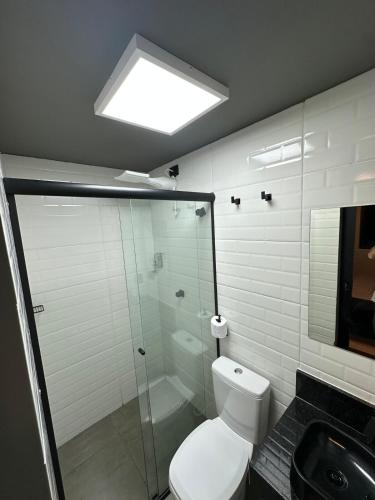 ein Badezimmer mit Toilette und Glasdusche in der Unterkunft Kit Aconchegante na Asa Norte - Centro in Brasilia