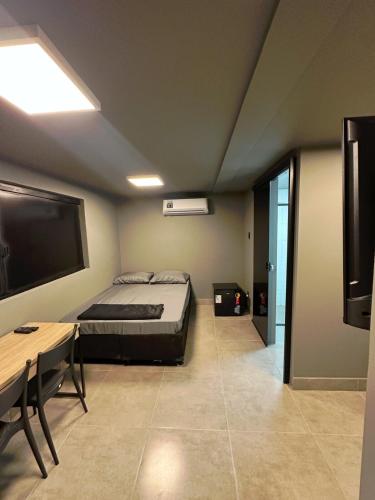 ein Schlafzimmer mit einem Bett, einem Fernseher und einem Tisch in der Unterkunft Kit Aconchegante na Asa Norte - Centro in Brasilia