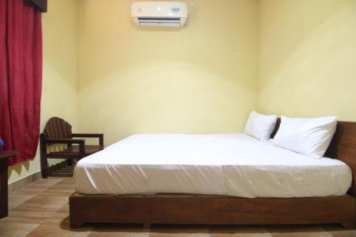a bedroom with a white bed with a air conditioner at Pondok Wisata Karapyak Jajapin in Nusa Were