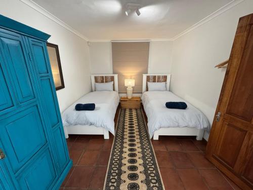 a room with two beds and a blue door at San Ma Lou in Paternoster