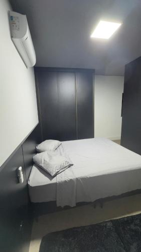 a small bedroom with a bed with white sheets at Rooftop Studio Premium in Bom Despacho