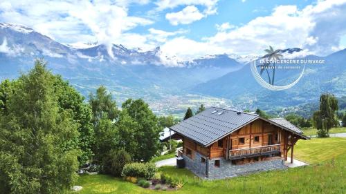 a house on a hill with mountains in the background at Chalet neuf La Marmotière - Vue sur la Montagne in Combloux