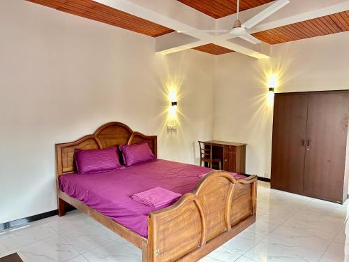 a bedroom with a wooden bed with purple sheets at FAM Hotel in Unawatuna