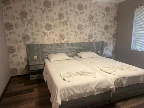 a bedroom with a bed with white sheets and a bow on it at Комплекс Хиподрума in Dobrich