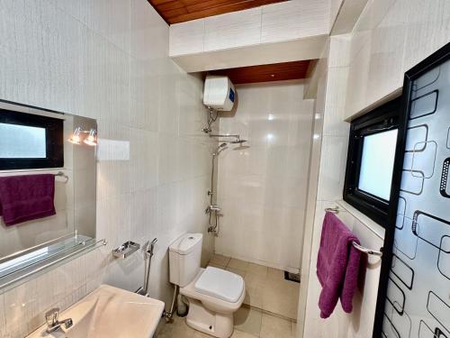a white bathroom with a toilet and a sink at FAM Hotel in Unawatuna