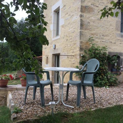 two chairs and a table in front of a building at Les Tanneries in Flavigny-sur-Ozerain