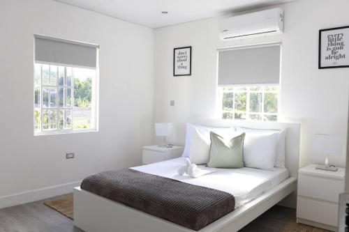une chambre blanche avec un lit et deux fenêtres dans l'établissement Eshae Living - Cosy 2BR with breakfast & pool, à Stanmore Grove
