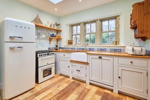 a kitchen with white appliances and wooden floors at Host & Stay - Sonsy Cottage in Alnmouth