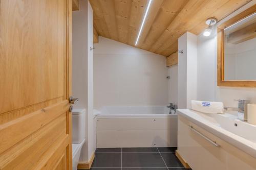 een badkamer met een wit bad en een wastafel bij Combe Humbert Apartment - Snow and Trek- Morzine in Morzine