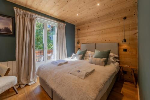 een slaapkamer met een groot bed en een raam bij Combe Humbert Apartment - Snow and Trek- Morzine in Morzine