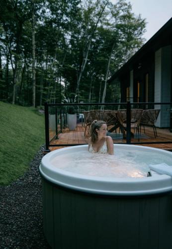 a woman in a hot tub in a yard at Zen House 5 - Villas & Spa in Lac-Superieur