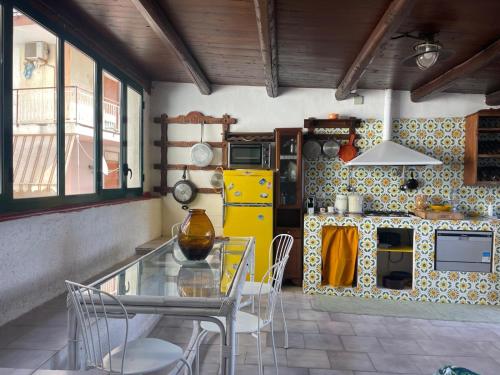 a kitchen with a glass table and a yellow refrigerator at Casa del Sorriso in Isola delle Femmine