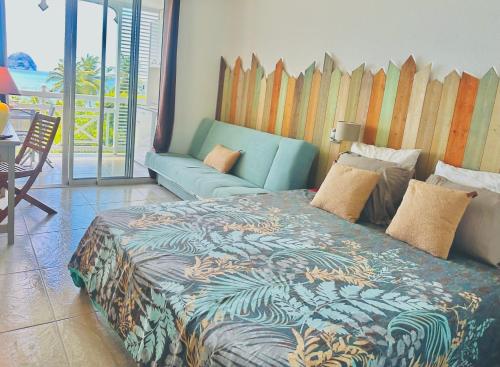 une chambre avec un grand lit et un canapé dans l'établissement Studio 2/4 personnes avec vue mer & piscine - Résidence Marinotel, au Diamant