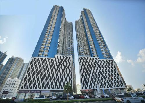 two tall buildings with cars parked in a parking lot at 2BHK apt Creek view Ajman UAE in Ajman