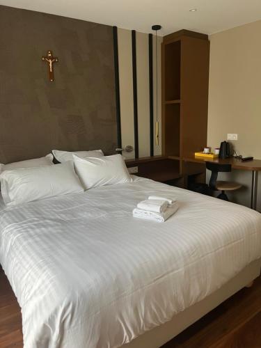 een slaapkamer met een wit bed met een kruis aan de muur bij Centre de la Solitude du Sauveur in Le Mans