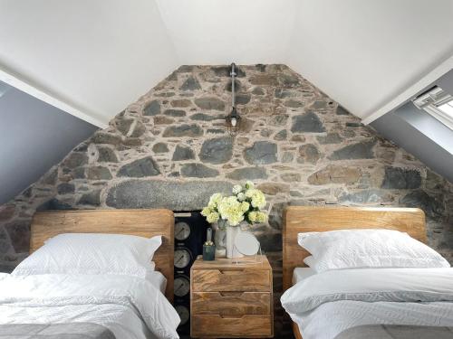 two beds in a room with a stone wall at Pink Cottage in Kirkcowan