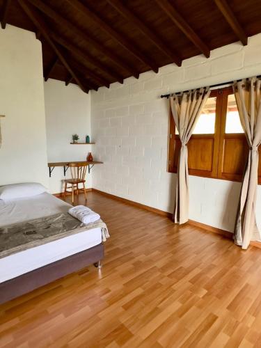 a bedroom with a bed and a wooden floor at Entre Cafetales in Jardin